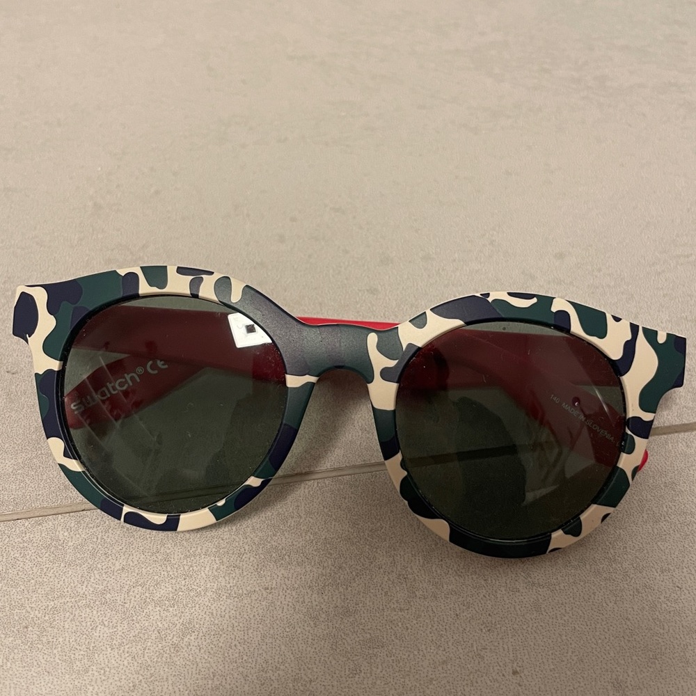never used swatch sunglasses in navy blue and white camo print and red legs.